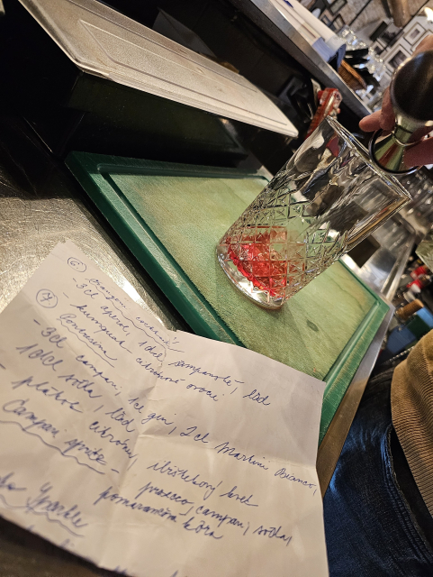 barman pripravuje miešaný drink, v popredí papier s receptúrou
