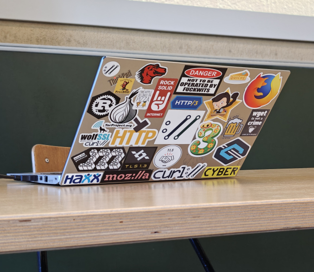 Daniel's laptop, covered in various stickers, among them Firefox, multiple Mozilla stickers, a curl sticker, one for Tor, and a WGet one, too!