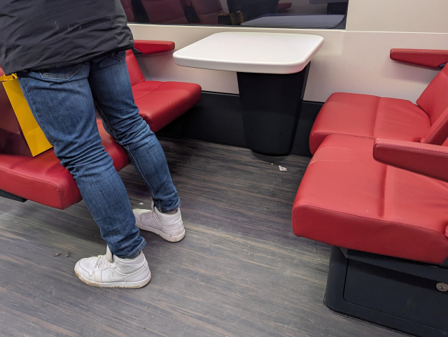 A group of red seats. Someone is standing next to one seat. A white footstep is visible on one of the seats.