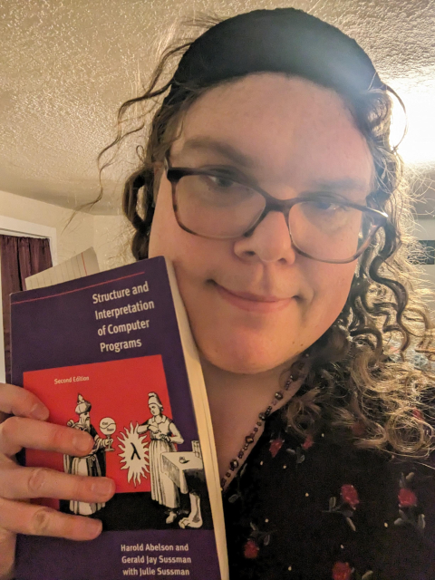 Christine holding a copy of SICP to her face