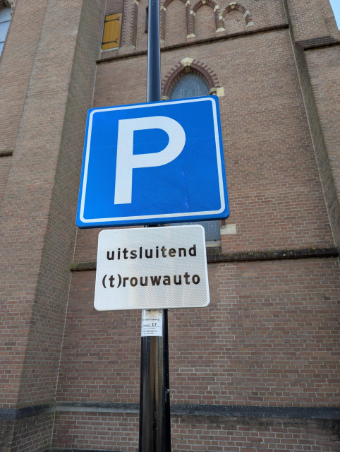 A parking traffic sign in front of a church. 

A sign under it reads:

uitsluitend
(t)rouwauto
