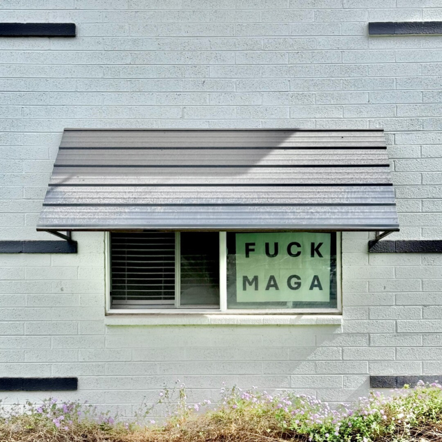 Apartment window with a handmade sign that says "FUCK MAGA"