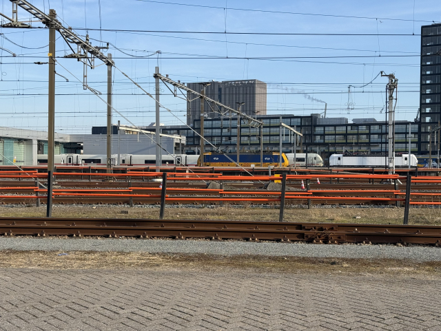 Snapshot across a rail yard. In the far distance you can see a white train with very short carriages headed by a white Vectron.