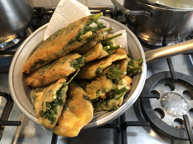 Una coladera llena de huauzontles con queso recién capeados y fritos, listos para navegar en salsa verde.