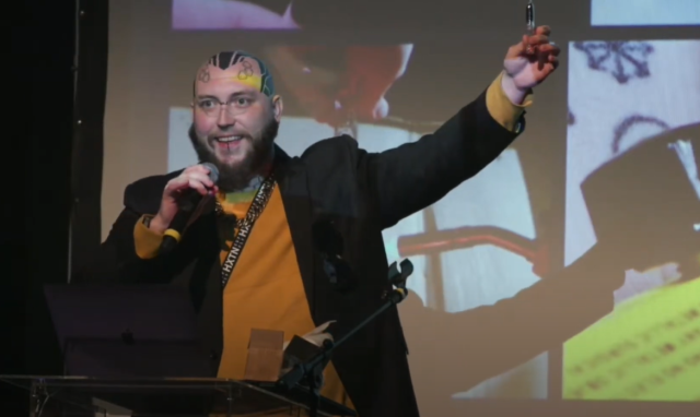 Screenshot from my Supercon 2022 appearance. I'm holding a microphone in one hand and a handmade vacuum diode in the other.