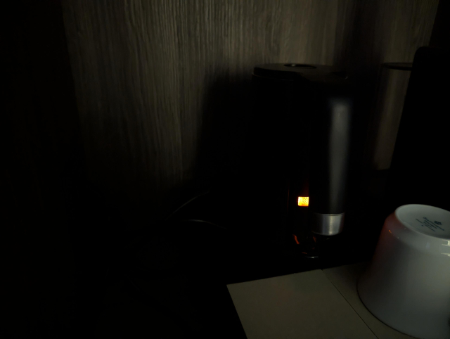 A small kettle in a cabinet, apparently turned on.