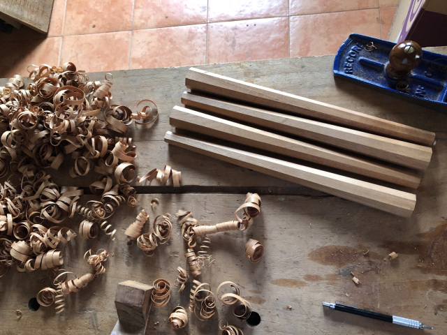 Las cuatro patas octagonales terminadas, junto a un montoncito de viruta. Sigue tallarles las espigas.