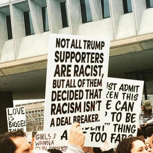 Protest, one sign reads "NOT ALL TRUMP SUPPORTERS ARE RACIST BUT ALL OF THEM DECIDED RACISM ISN'T A DEAL BREAKER"