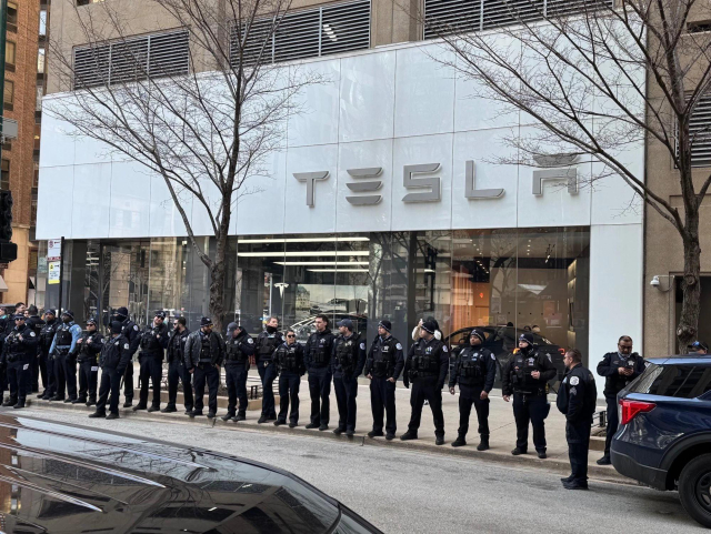 Image of dozens of police lining up to protect a Tesla dealership.