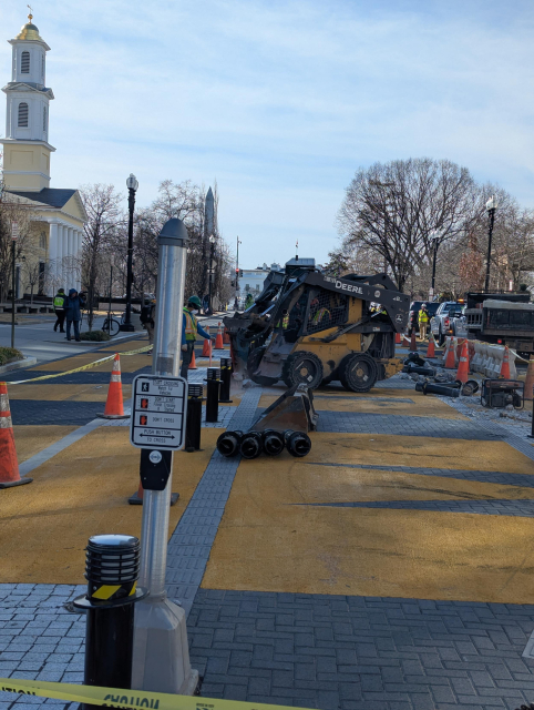 A hydraulic hanmer digging up the street on Black Lives Matter Plaza. At John's Church, the Washington Monument, and the White House are visible in the background.