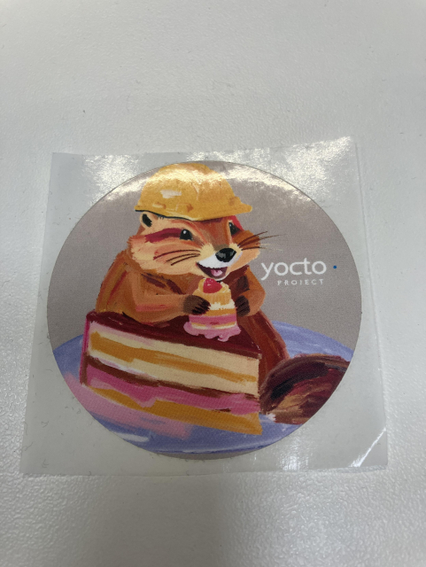 A round sticker for the Yocto Project, showing a cartoon beaver with a hard hat working on a slice of cake
