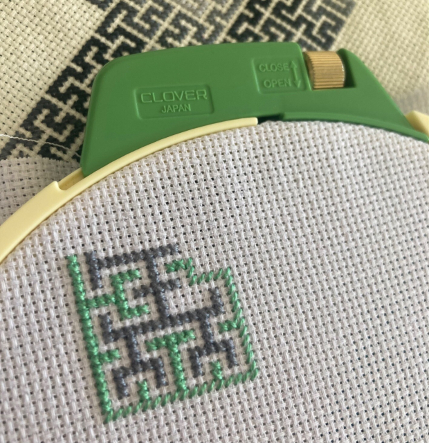 Green and gray cross-stitch leaving most of a third-iteration Hilbert curve as the white background between the green and gray regions