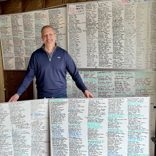 Guy with a Ford shirt poses in front of 5 whiteboards that serve as leaderboards ranking the best-ever mis-spoken phrases of coworkers. A few examples: reasonable reasons, wrotten, unpresidented — but there are so many more, and they are delightfully chaotic in a way that your descriptive AI is quite unprepared for 