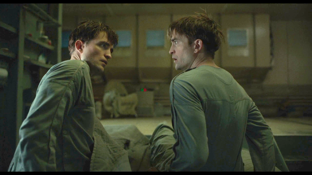 Screenshot from the film Mickey 17 (2025). Two identical humans, both clones with one that is supposed to replace the other, looking at each other in a state of disbelief.