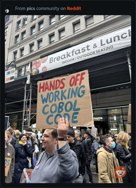 Someone holding up a protest sign that says "Hands off working COBOL code"