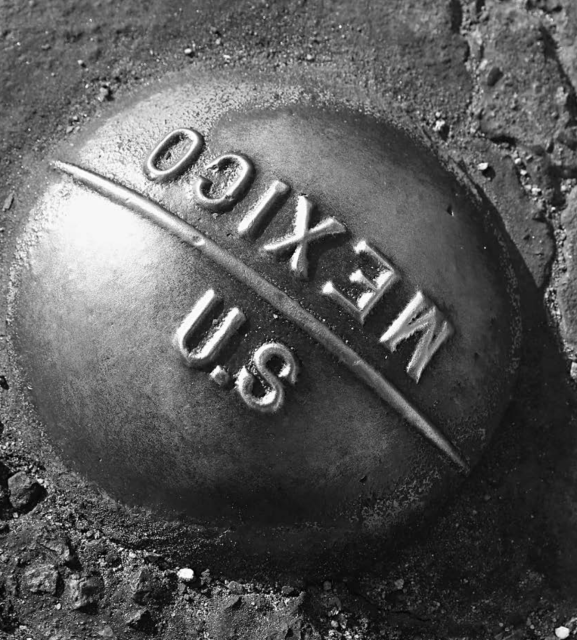 An image of a marker at the US-Mexico border, reading "US" on one side and "Mexico" on the other.