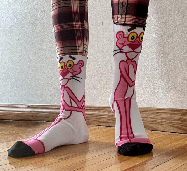 A shot below the knees of pink and black plaid leggings tucked into Pink Panther socks. 