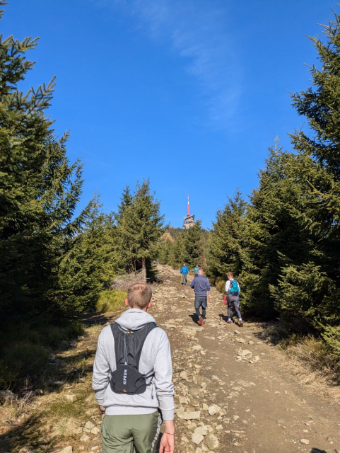 A trail to the top with several hikers. A transmission tower on the top is visible in the background.