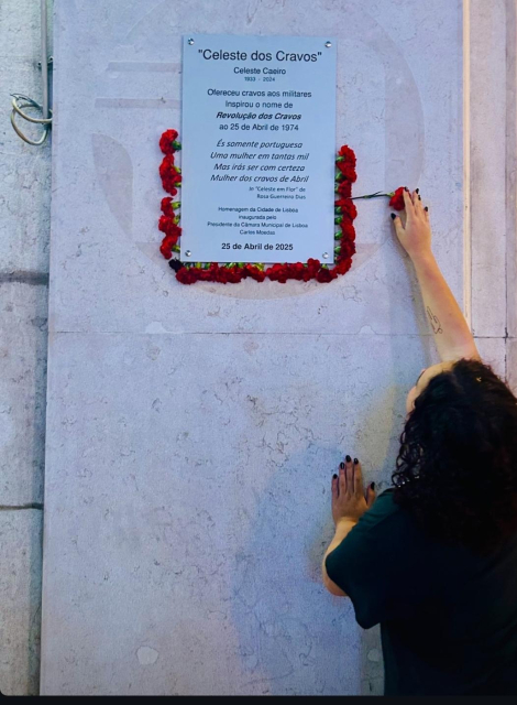 Placa comemorativa  a Celeste Caeiro inaugurada hoje no  o Rossio (Lisboa) com uma jovem a colocar um cravo. Texto placa:

Celeste dos Cravos"
Celeste Caeiro
1933 - 2024

Ofereceu cravos aos militares
Inspirou o nome de
Revolução dos Cravos

É somente portuguesa
Uma mulher em tantas mil
Mas irás ser com certeza
Mulher dos cravos de Abril

In "Celeste em Flor" de
Rosa Guerreiro Dias

Homenagem da Cidade de Lisboa
Inaugurada pelo
Presidente da Câmara Municipal de Lisboa


25 de Abril de 2025