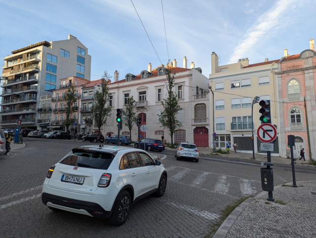 A picture of a junction. The street from view has an overhead wire and no rail, the street behind has rails and no overhead wires.