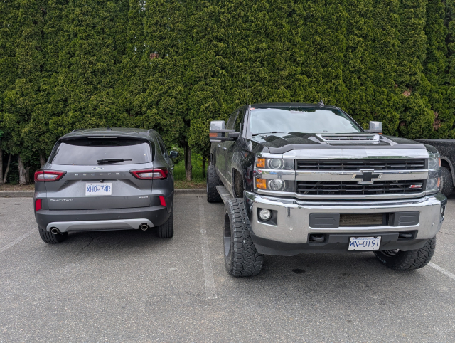 A Ford escape (small SUV) parked next to a huge, lifted truck..