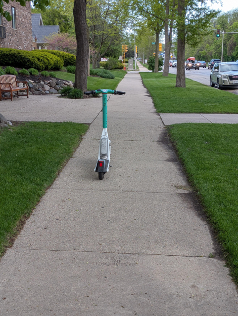 A lime scooter parked on the sidewalk