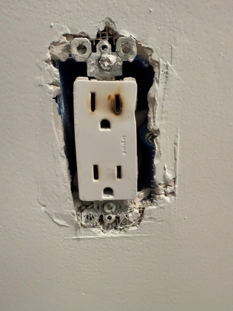 A US 120V power outlet, badly scorched and melted on the top socket. Very bad soup. 
