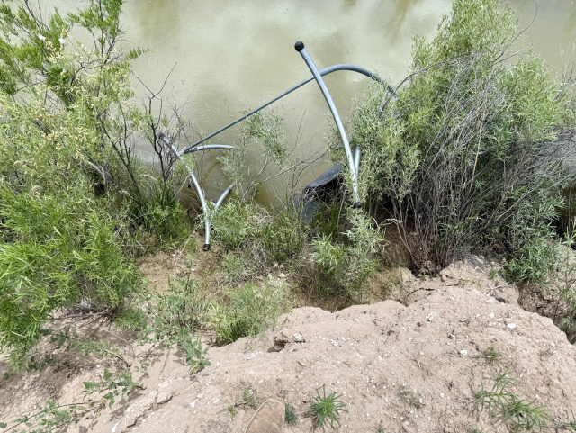 The image shows a swing set partially collapsed on a sandy embankment near a body of water. The swing's metal frame is visible, with a black seat attached, and it is leaning backward, suggesting it has fallen. The swing is positioned on a small mound of dirt, surrounded by sparse vegetation, including grasses and shrubs. A blue and white rope is laid out on the ground, possibly used for securing the swing or for another purpose. The background features a muddy waterway with more greenery along its banks. The scene appears to be in a natural, outdoor setting, possibly a park or a rural area.

Provided by @altbot@fuzzies.wtf, generated privately and locally using Ovis2-8B

🌱 Energy used: 2.574 Wh