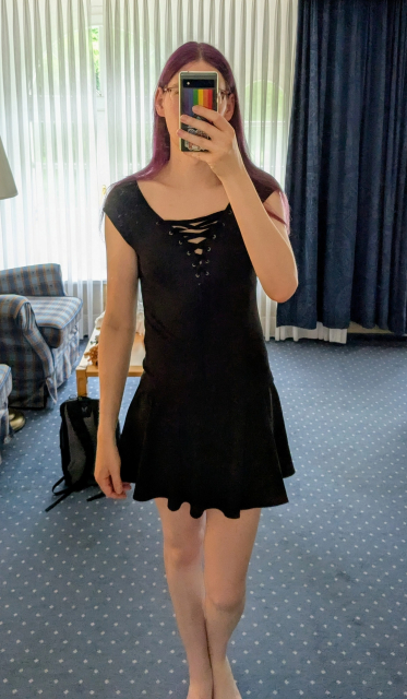Selfie von mir, mit neuem (schwarzen) Oberteil, und dazu meinem üblichen Rock. Das Gesicht wird wie üblich durch mein Smartphone verdeckt, die (lila) Haare trage ich ausnahmsweise offen.

Im Hintergrund sieht man noch meinen Rucksack, einen Teil von Rehbrand (meinem Plüsch-Reh), Teile eines Sessels, Vorhänge vor einem Fenster, sowie den Teppichboden.