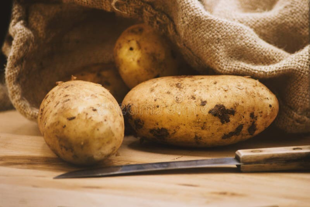 A picture of potatoes and a knife.