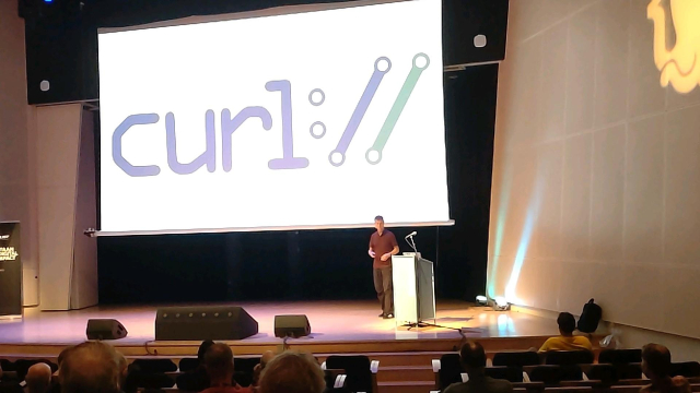 Daniel at Joy of Coding in front of a giant screen showing the curl logo