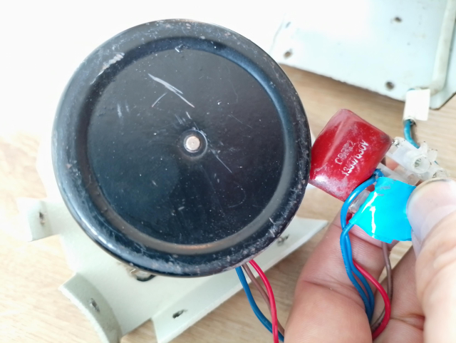 Parts of a projector screen. The engine is visible on the left (a black cylinder) and is connected with 4 wires to a brown block