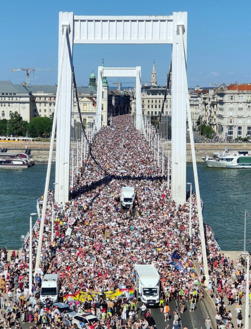 A huge crowd in Budapest today crossing a bridge a past of a Pride parade.