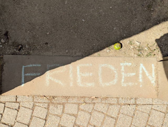 Auf einer Sandsteinschwelle eines Gartentores ist mit Kreide "Frieden" geschrieben