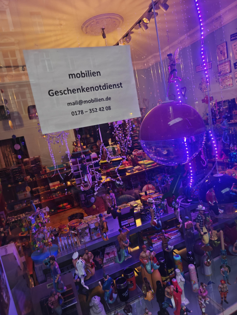 Pictures in front of a boutique selling man-mermaid with a schild seeing that they offer emergency gift service 