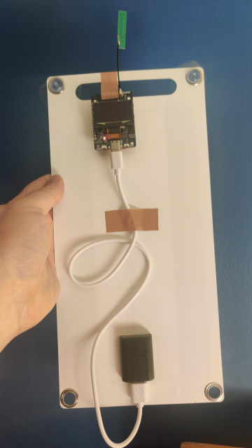 The back of the node, showing a small esp32 LoRa board attached to the back of a solar panel with cloth tape.

The solar panel is about eight fingers by ⅔ cubit in size.
