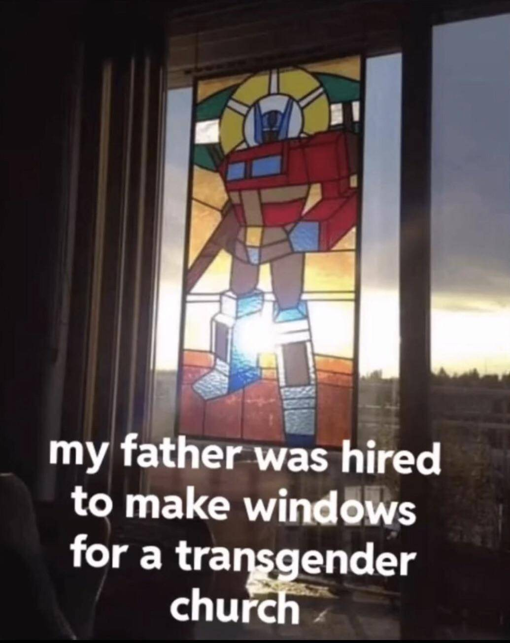 Stained glass window depicts Optimus Prime with halo. Text: my father was hired to make windows for a transgender church