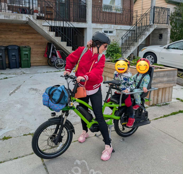 My friend with her two kids on the back of a bright green long-tail electric cargo bike