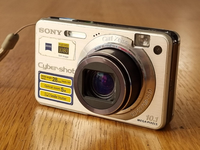 Fotka kompaktního fotoaparátu Sony Cybershot. 
https://cdn.aukro.cz/images/sk1686504802778/kompaktni-digitalni-fotoaparat-sony-cybershot-dsc-w170-162498896.jpeg