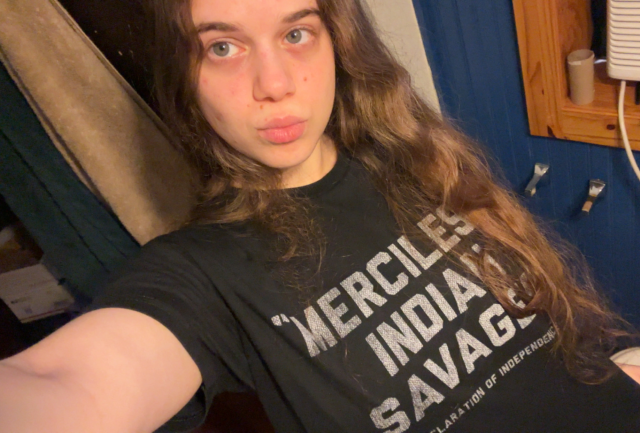 Selfie of me in a black t-shirt with white text that reads "Merciless Indian Savages -Declaration of Independence". I have my hair down and I'm making a duck face.