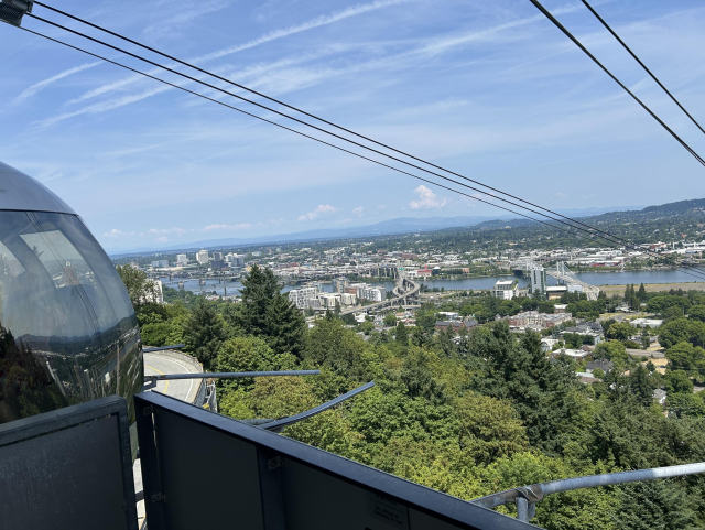 A view from the platform at The top of the aerial tram, with pod peaking out at the left and portland landscape down below, with river running across