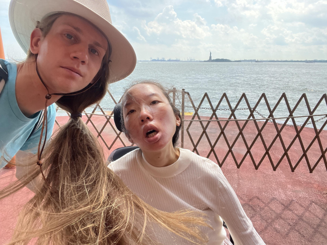 A selfie of Aubrie and Peter at the very front of the ferry, with the Statue of Liberty in the background.