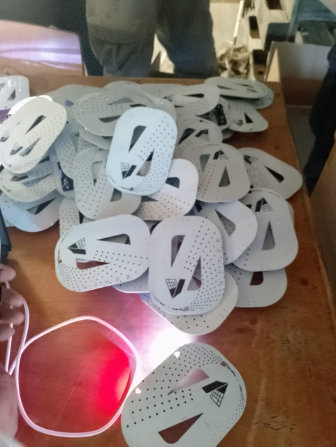 A lot of white printed circuit boards in the shape of a zero. They are on a pile on a table