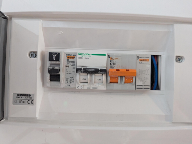 A distribution box with one 2-pole 25/0,03A RCD, two 2-pole C10 circuit breakers a relay and an empty uncovered slot.