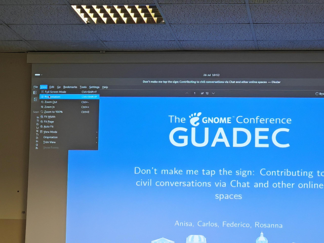 Photo of a GNOME GUADEC presentation with the Okular titlebar and menu open.