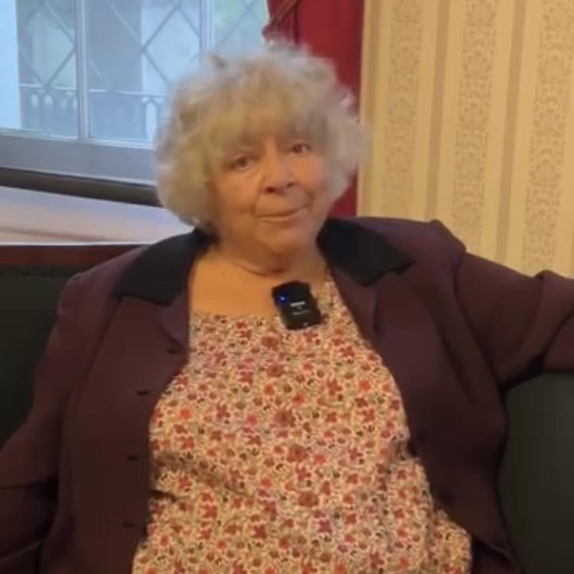 Miriam Margolyes, with pursed lips, seated in a floral dress, as she contemplates what is happening in Gaza. 