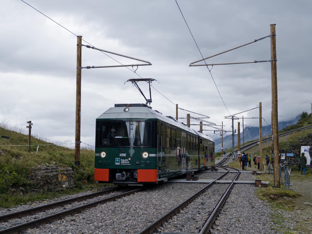 Moderner grüner Triebwagen in einer Ausweiche in bergiger Lage