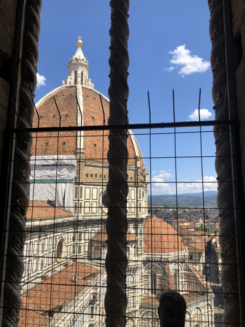 Brunelleschi's brick dome on Santa Maria de Fiore, in Firenze, seen from up high on the campanile. A few fluffy clouds in the beautiful blue sky.