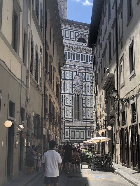 View of the north apse of Florence cathedral, or part of it, framed between buildings on a street that leads to it.