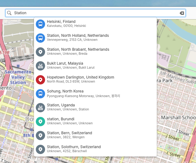 A screenshot of elementary maps, cropped in on search results. Each result has an icon in a colored circle next to it. For example a bus or train icon in a blue circle or a city skyline icon in a grey circle. 